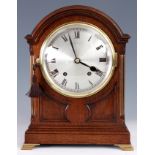 AN EDWARDIAN DOME TOP OAK MANTEL CLOCK with panelled front and ogee bracket feet, silvered convex