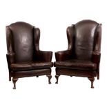 A PAIR OF GEORGE I STYLE OAK BROWN LEATHERED WINGBACK ARMCHAIRS with shaped scrolled arms and