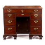 A GEORGE III MAHOGANY KNEEHOLE DESK with moulded edge top above a configuration of eight drawers