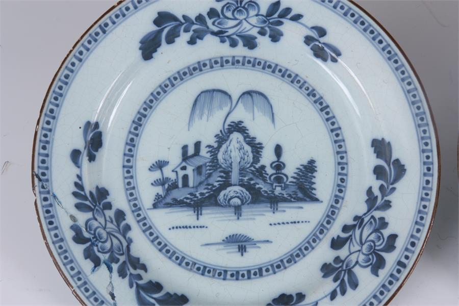 A PAIR OF 18TH CENTURY ENGLISH BLUE AND WHITE DELFT PLATES with landscape centres and leafing flower - Image 4 of 10