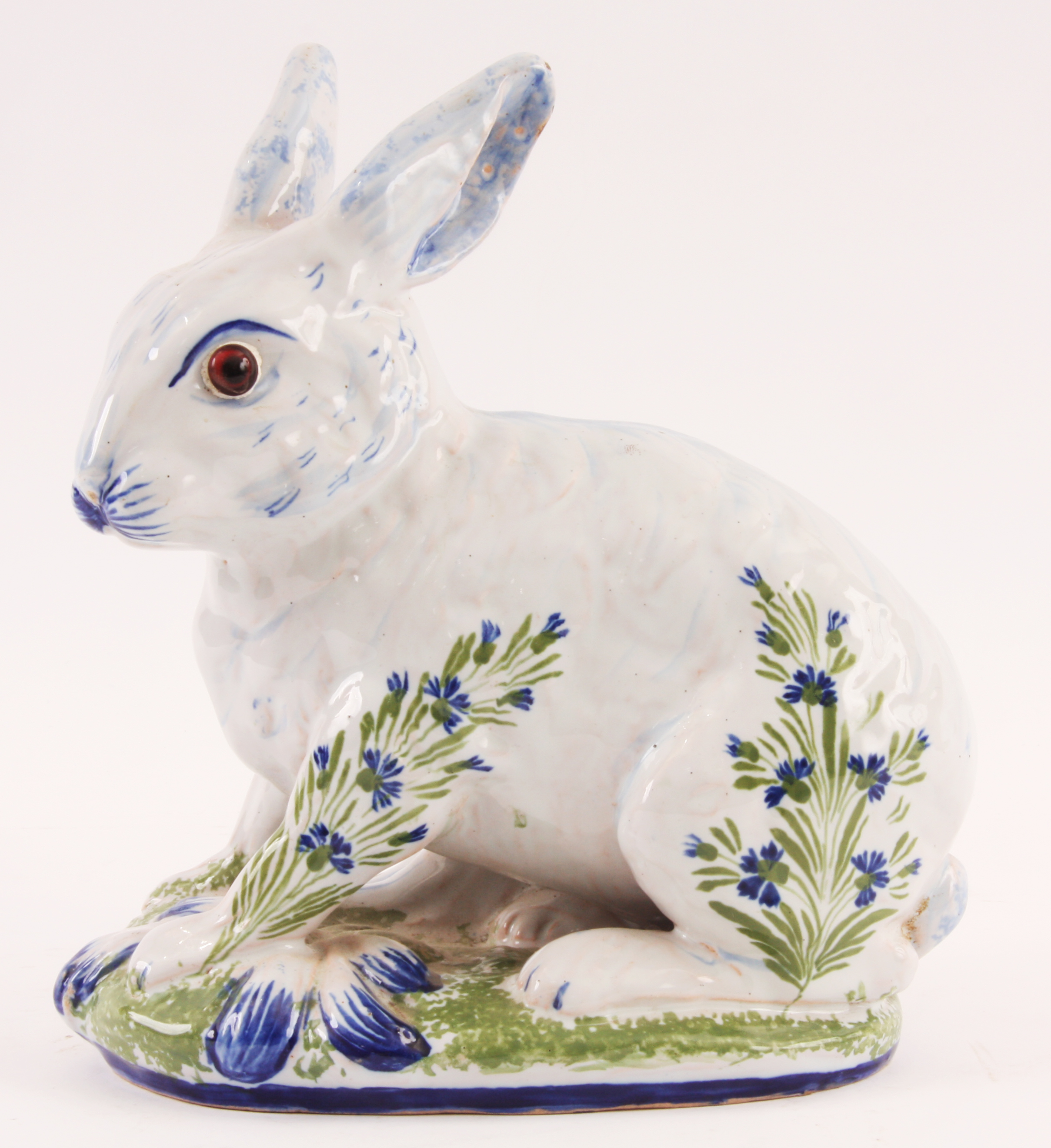 A DELFT STYLE GLAZED SEATED RABBIT with amber eyes and decorated flower spray decoration, the