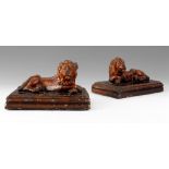 A PAIR OF 19TH CENTURY TREACLE GLAZED STAFFORDSHIRE RECUMBENT LIONS on moulded plinth bases 25cm