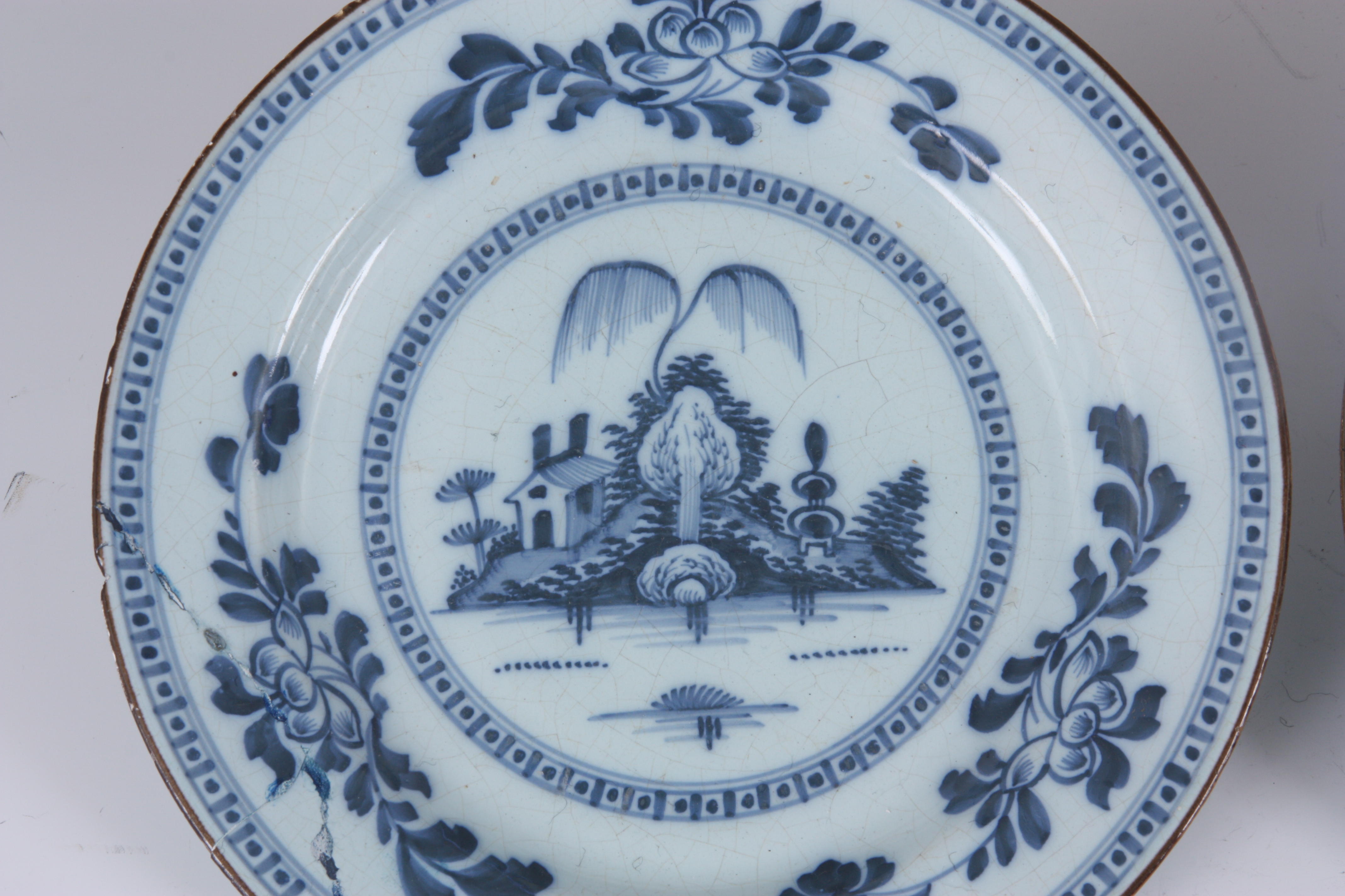 A PAIR OF 18TH CENTURY ENGLISH BLUE AND WHITE DELFT PLATES with landscape centres and leafing flower - Image 8 of 10