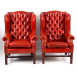 A PAIR OF 19TH CENTURY STYLE RED LEATHER BUTTON BACKED WINGED ARMCHAIRS with deep buttoned backs,