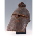 A 19th CENTURY NIGERIAN HARDWOOD HELMET MASK with comical face and red cloth stuck to the back,