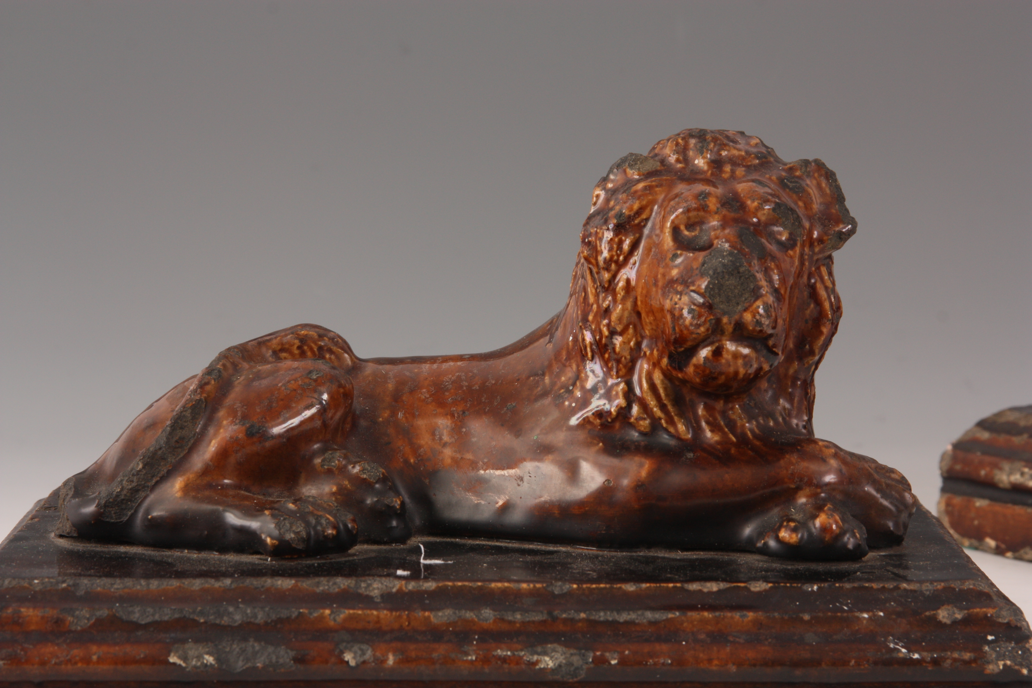 A PAIR OF 19TH CENTURY TREACLE GLAZED STAFFORDSHIRE RECUMBENT LIONS on moulded plinth bases 25cm - Image 2 of 5