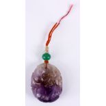 AN EARLY 20TH CENTURY CARVED AMETHYST PENDANT formed as fruit branch suspended with orange cord with