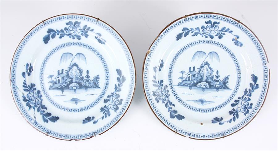 A PAIR OF 18TH CENTURY ENGLISH BLUE AND WHITE DELFT PLATES with landscape centres and leafing flower - Image 2 of 10