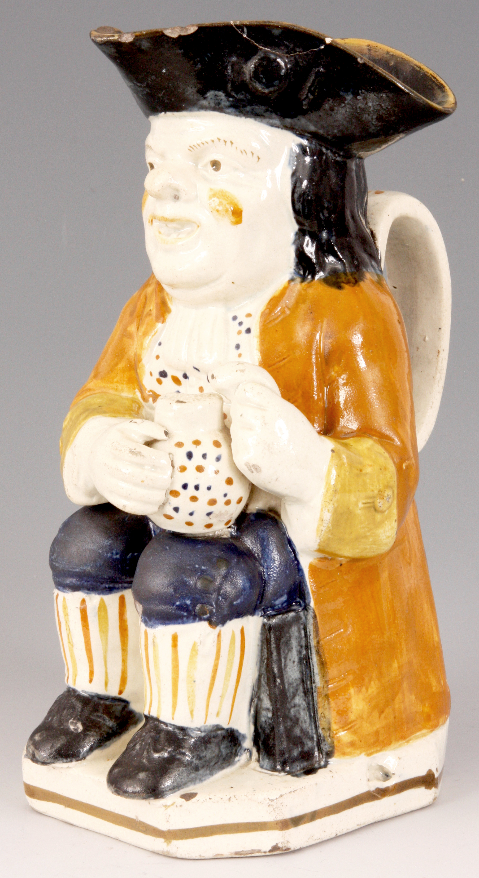 A GEORGE III STAFFORDSHIRE TOBY JUG the seated man holding a jug of ale in ochre hat with mustard