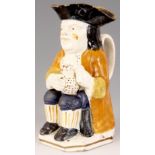 A GEORGE III STAFFORDSHIRE TOBY JUG the seated man holding a jug of ale in ochre hat with mustard