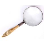 A LATE 19TH CENTURY MAGNIFYING GLASS with shaped reeded ivory handle and silver collar with embossed