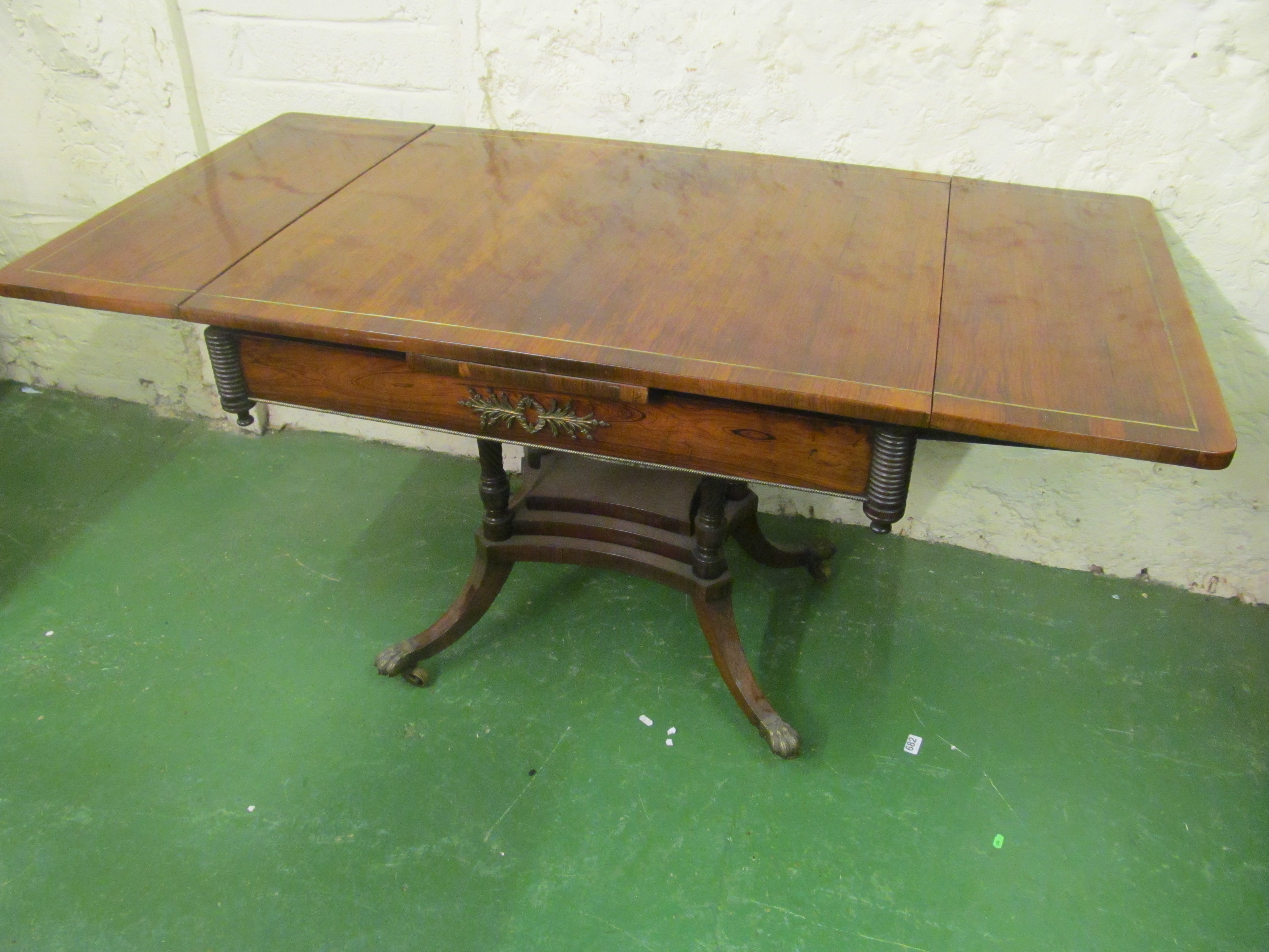 A rosewood Regency style drawleaf table on four pillar supports and splay legs.