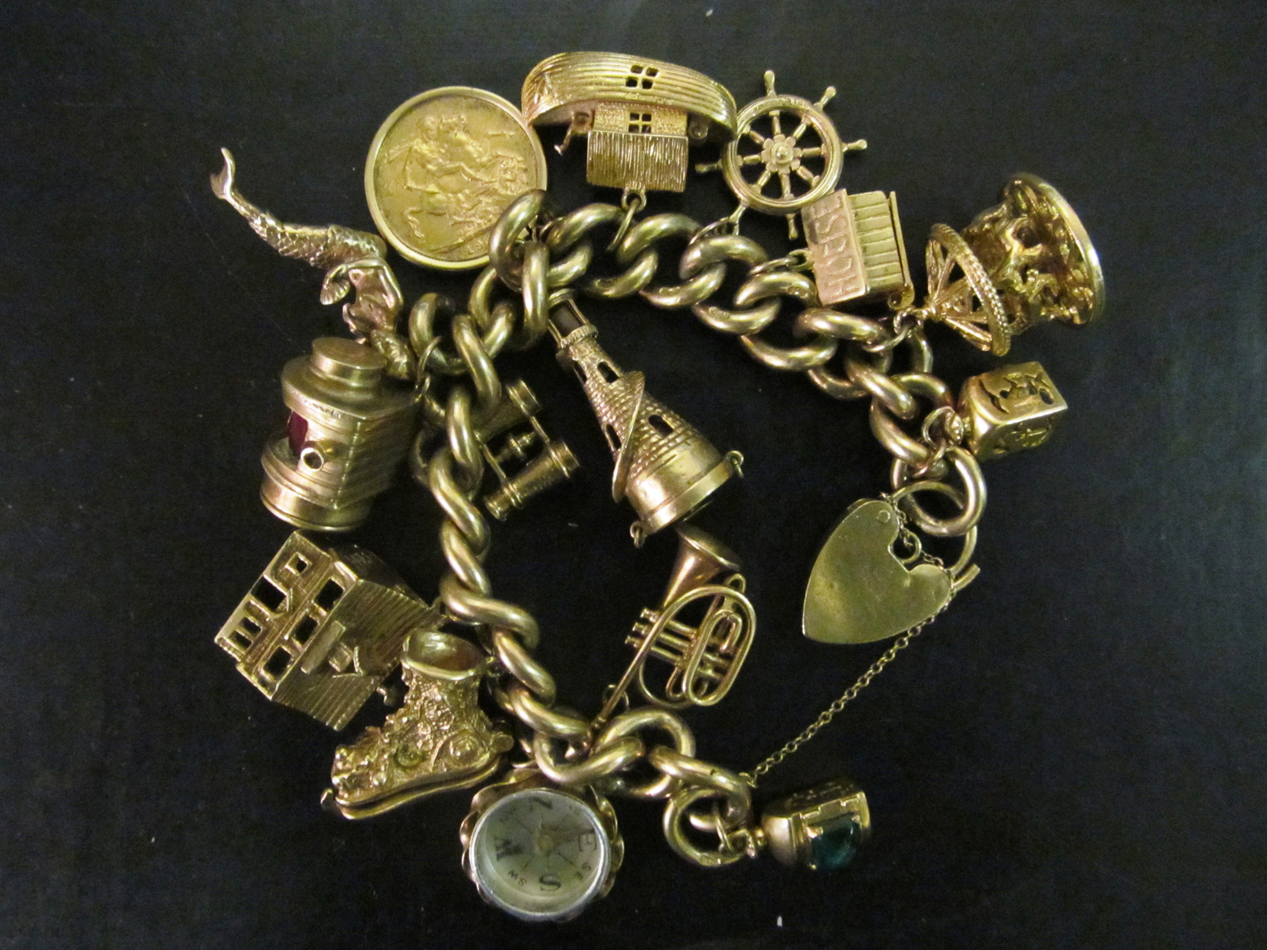 A 9ct gold charm bracelet with Sovereign and other charms