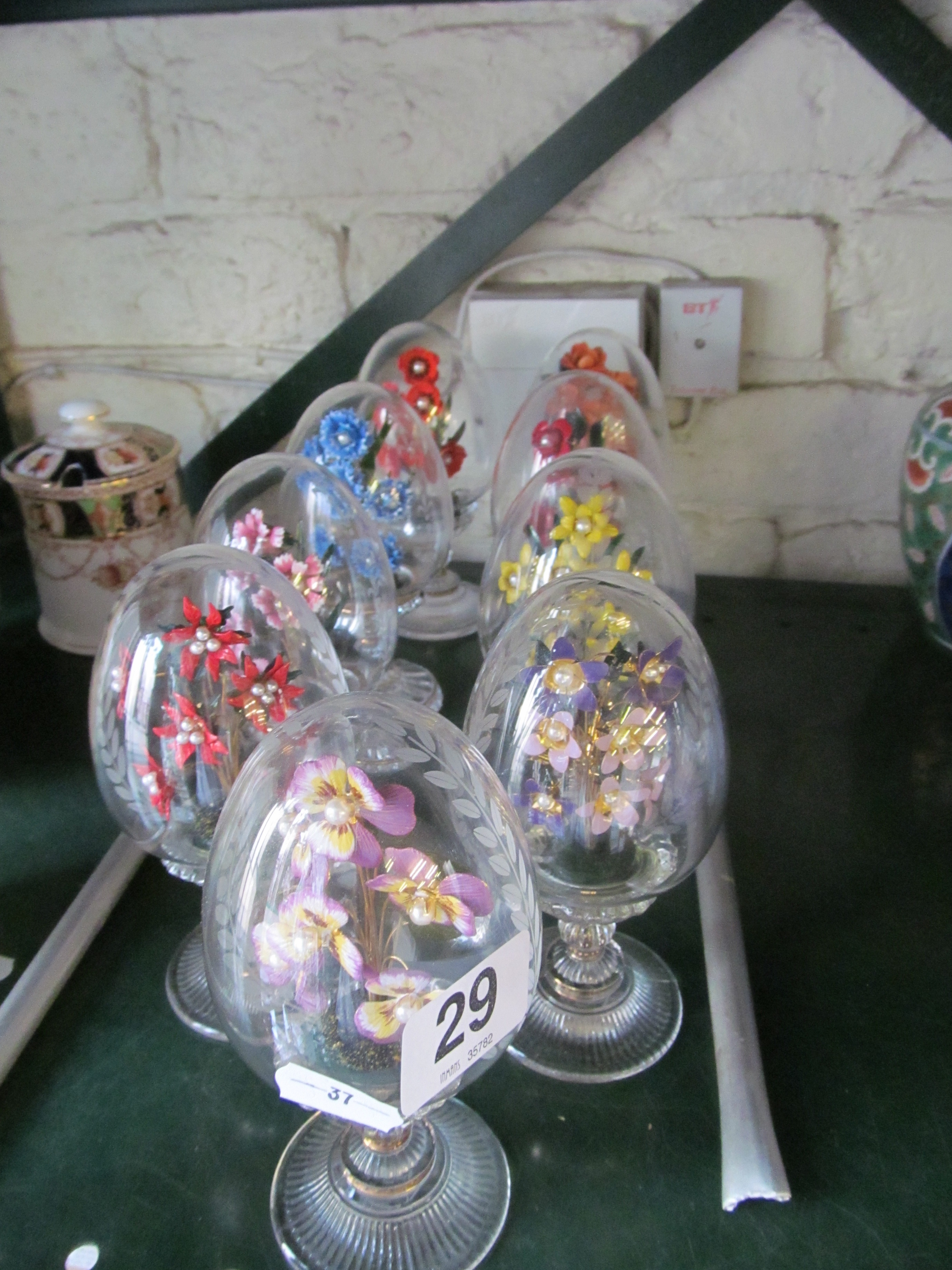 Nine Franklin Mint enamel flowers in glass eggs