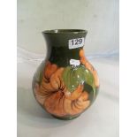 A Moorcroft baluster vase of green ground and pink flowers.
