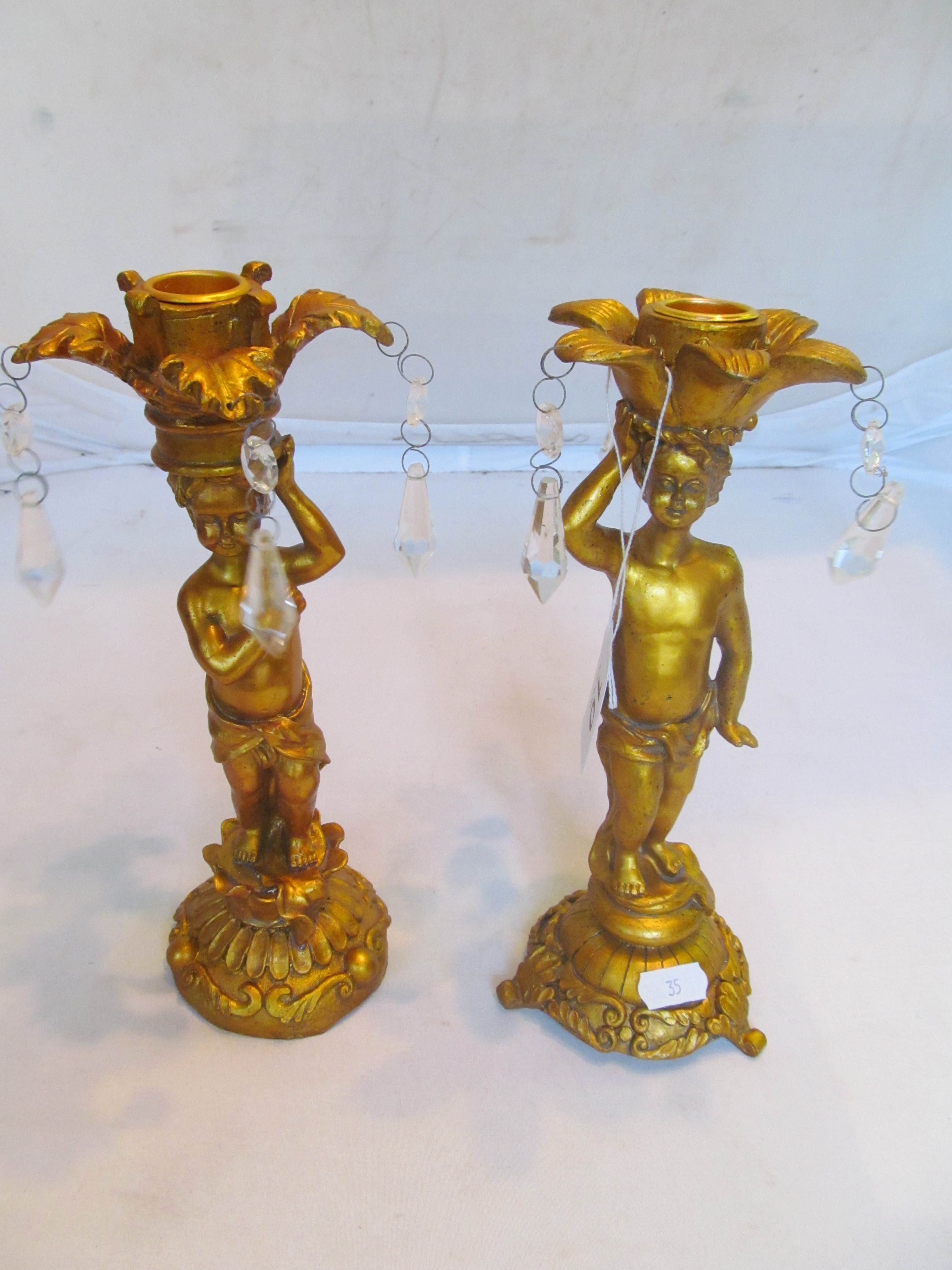 A pair of gilt cherub candlesticks with lustre drops