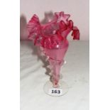 A cranberry glass fluted vase with frilled decoration.