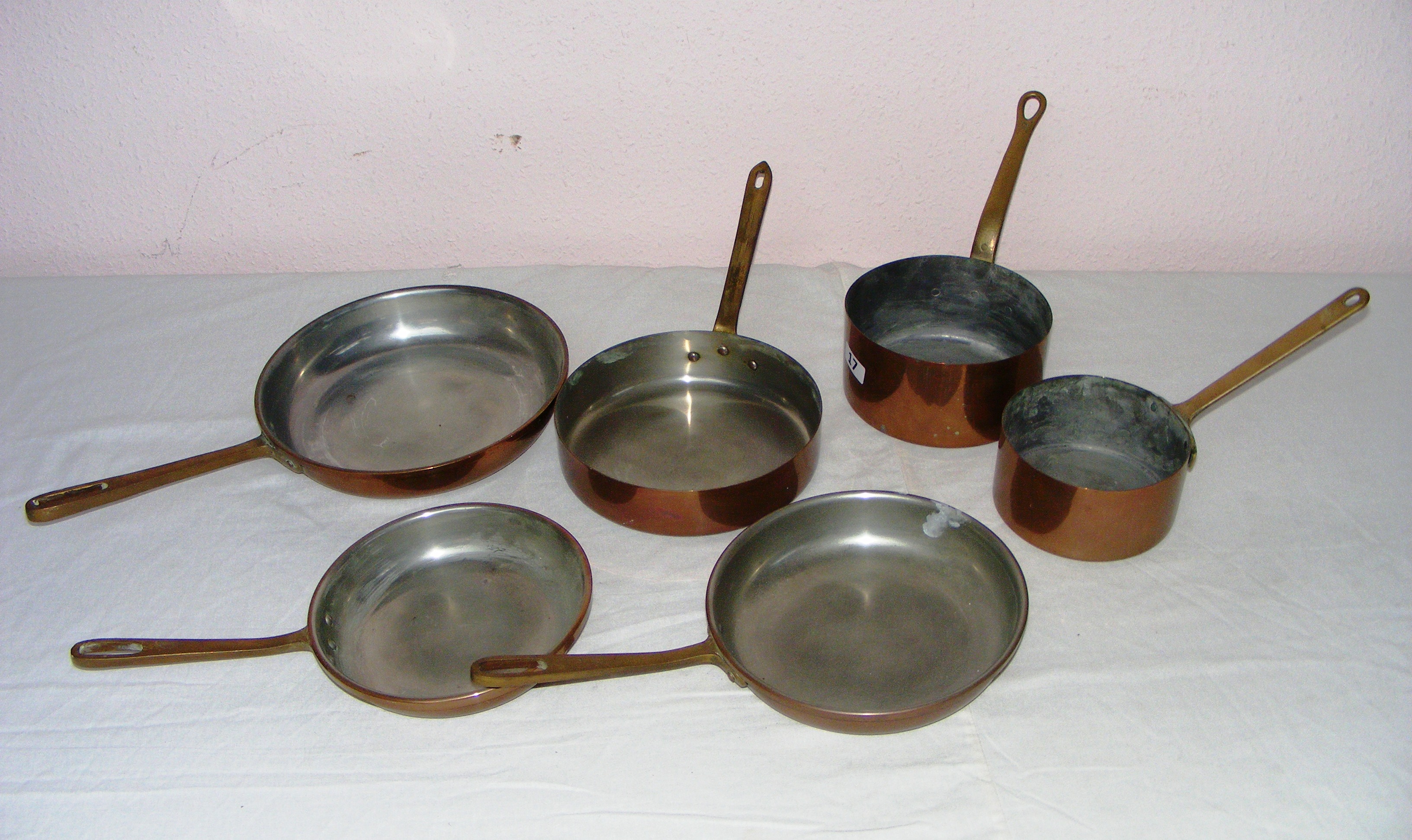 Six assorted copper pans with brass handles.