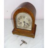 A dome shaped oak mantle clock with key and in ticking condition.