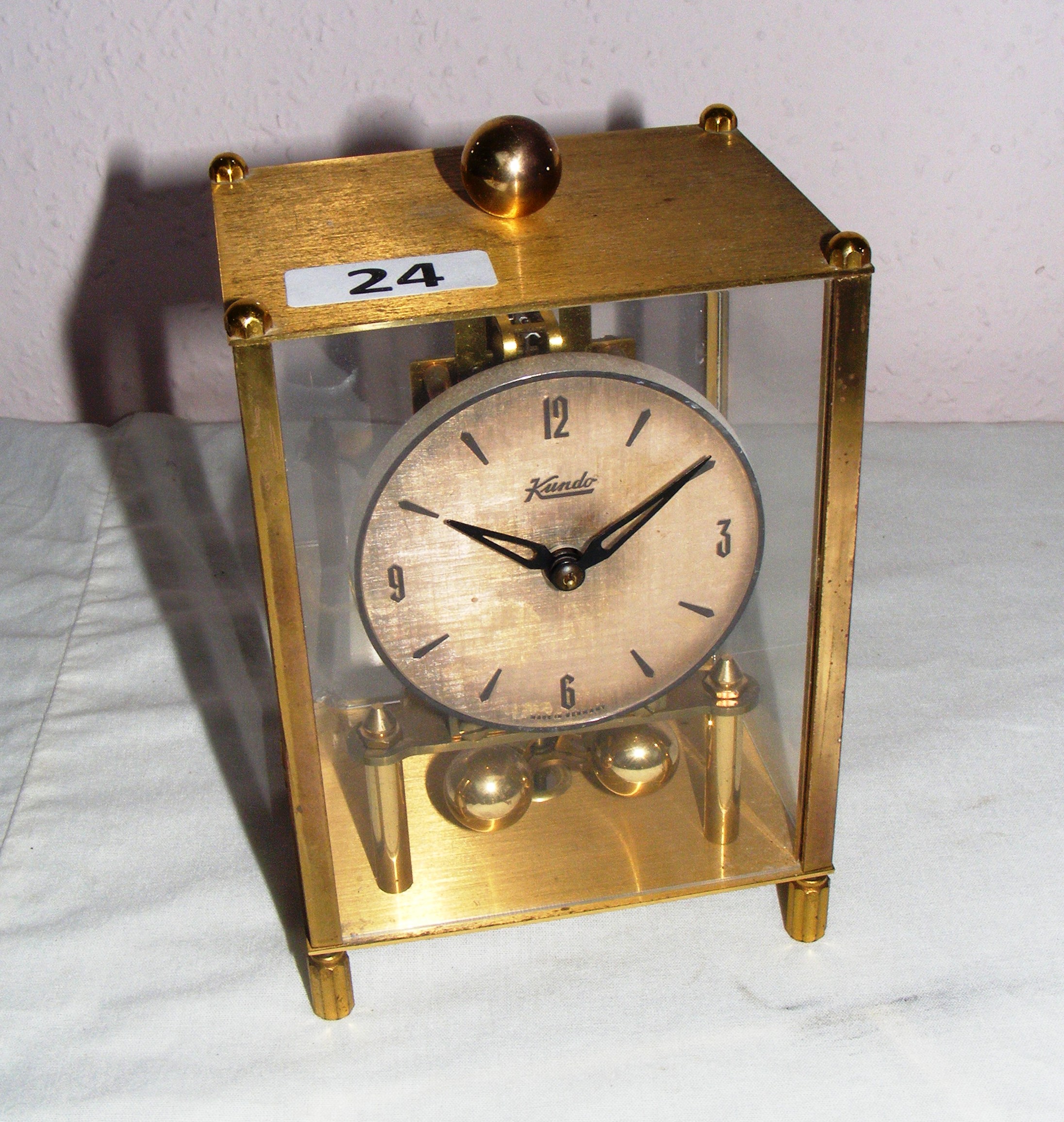 A Kundo Anniversary Clock with Kieninger & Oberdfell Movement, in a square glass case 6.75" tall.