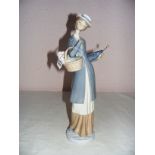 A Nao figurine of a lady with a basket and parasol measuring 14" tall.