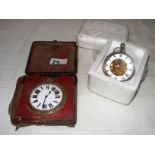 A large bevel wind base metal pocket watch in a fitted case and a modern glass mystery clock.