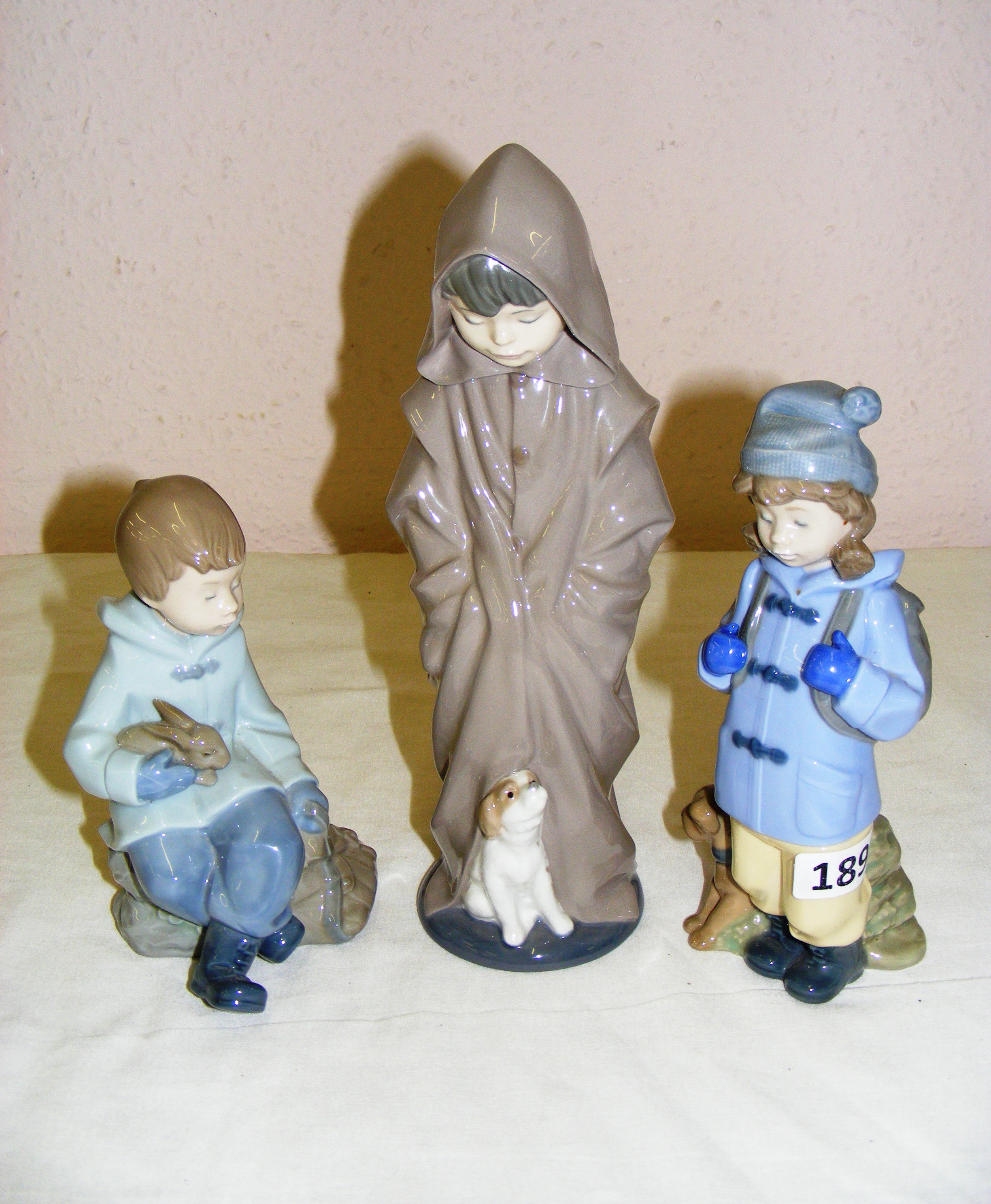 Three porcelain Nao figurines including a boy with a dog hiking,