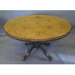 A Victorian Walnut Marquetry Inlaid Oval Centre Table with a quadruple turned centre column and