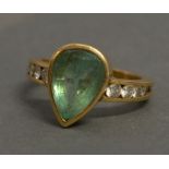 An Unmarked Gold Dress Ring set with a teardrop emerald flanked by diamonds, 6.