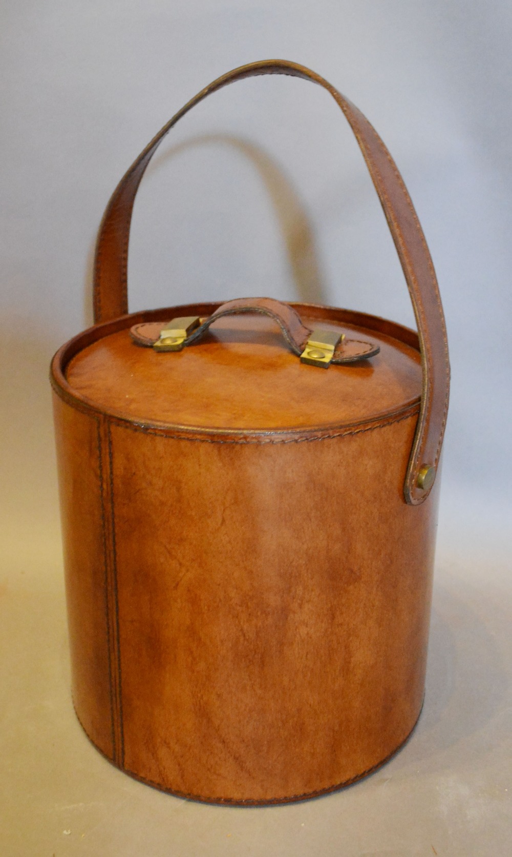 A Leather Travelling Wine Cooler of Circular Form with Tongs