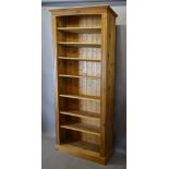 A Tall Pine Bookcase, the moulded top above an arrangement of shelves raised upon a plinth,