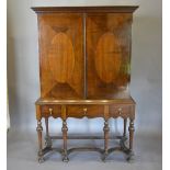 A Queen Anne Style Walnut Cabinet on Stand, the moulded cornice above two oval inlaid doors,