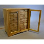 A 20th Century Hardwood Collectors' Cabinet with two glazed doors enclosing eighteen drawers with