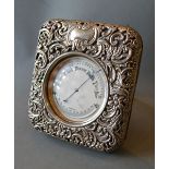 A Late 19th Century Large Table Barometer Thermometer within a silver case decorated in relief with