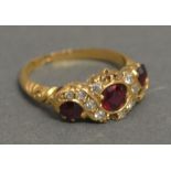 An 18ct Yellow Gold Ruby and Diamond Ring set with three rubies surrounded by diamonds within a