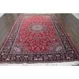 A North West Persian Woollen Carpet with a central medallion within an all over design upon a red,