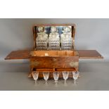 A Late Victorian Oak Tantalus with three decanters and stoppers above a double hinged compartment