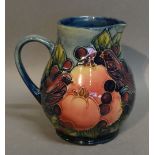 A Moorcroft Jug with Pomegranate Pattern, tube lined upon a green and blue ground,