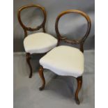 A Pair of Victorian Walnut Balloon Back Side Chairs each with a carved back above a serpentine over