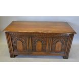 A 20th Century Green Oak Coffer, the plank top above three carved panels flanked by stiles,