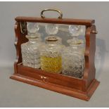 A Mahogany Tantalus with Three Cut Glass Decanters with Stoppers and Silver Plated Mounts