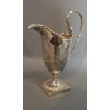 A George III Silver Helmet Shaped Cream Jug with shaped handle and square pedestal base,