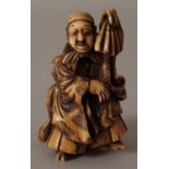 A JAPANESE MEIJI PERIOD STAINED IVORY OKIMONO OF A STREET PERFORMER, in the company of his son,