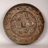 A CHINESE TANG STYLE SILVERED BRONZE MIRROR, decorated in relief with mythical creatures and vine,