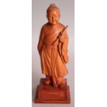 A GOOD QUALITY CHINESE COMMUNIST PERIOD CARVED WOOD FIGURE OF A STANDING SAGE, supported on a square