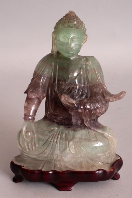A 20TH CENTURY CHINESE FLUORITE CRYSTAL CARVING OF BUDDHA, together with a fitted wood stand, the