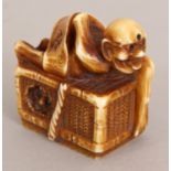 A SIGNED JAPANESE MEIJI PERIOD STAINED IVORY NETSUKE OF A DEMON, wrapped in a scroll and lying on