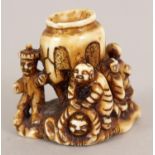 A SIGNED JAPANESE STAINED IVORY NETSUKE OF A GROUP OF BOYS, surrounding an urn supported on a