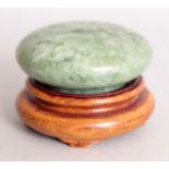 A 20TH CENTURY CHINESE JADE SHALLOW CIRCULAR BOX & COVER, together with a wood stand, the stone of