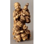 A SIGNED JAPANESE MEIJI PERIOD STAINED IVORY OKIMONO OF A PUPPETEER, in the company of his son and